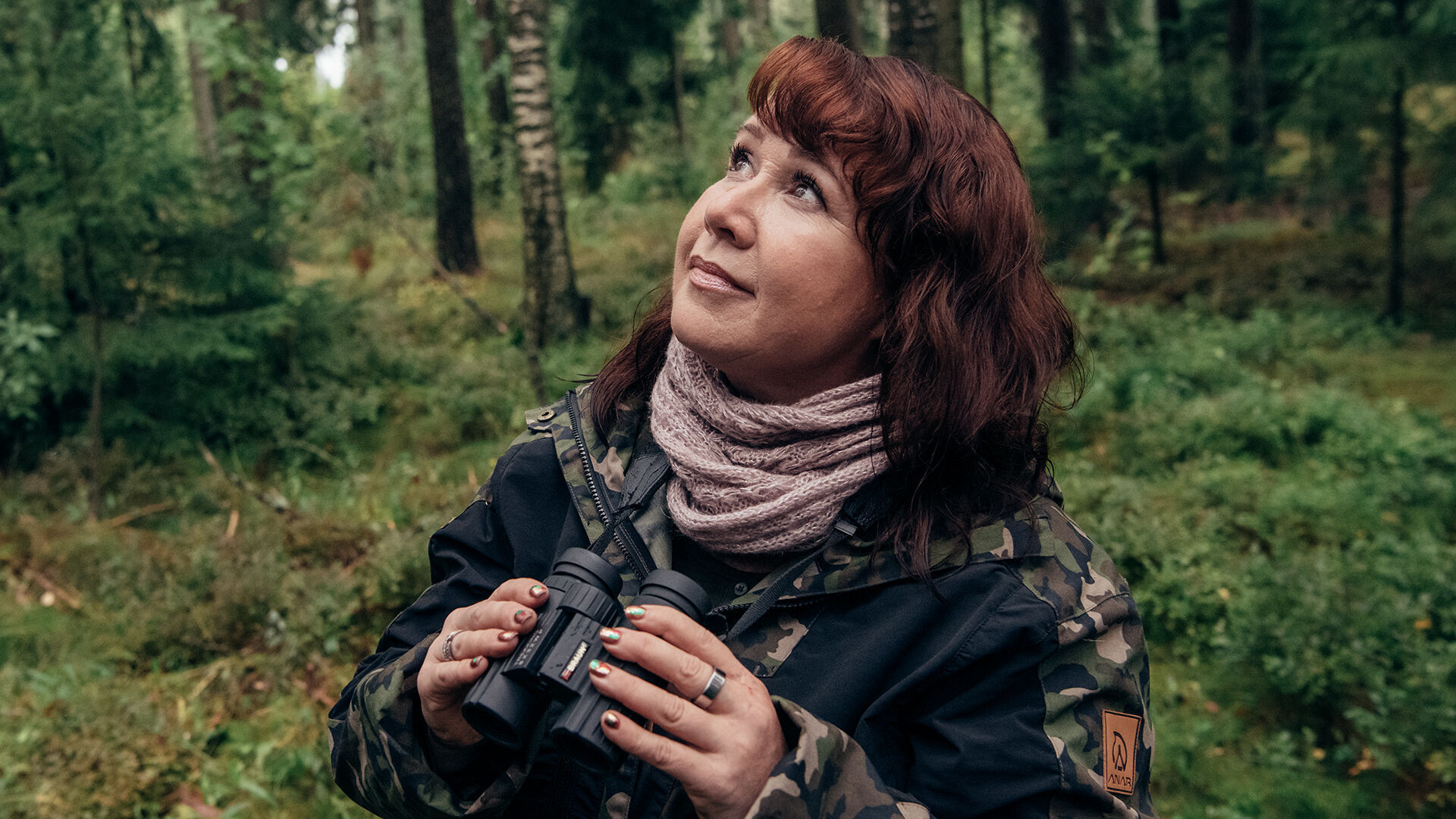 Nainen mets&auml;ss&auml; kiikarit k&auml;dess&auml;&auml;n